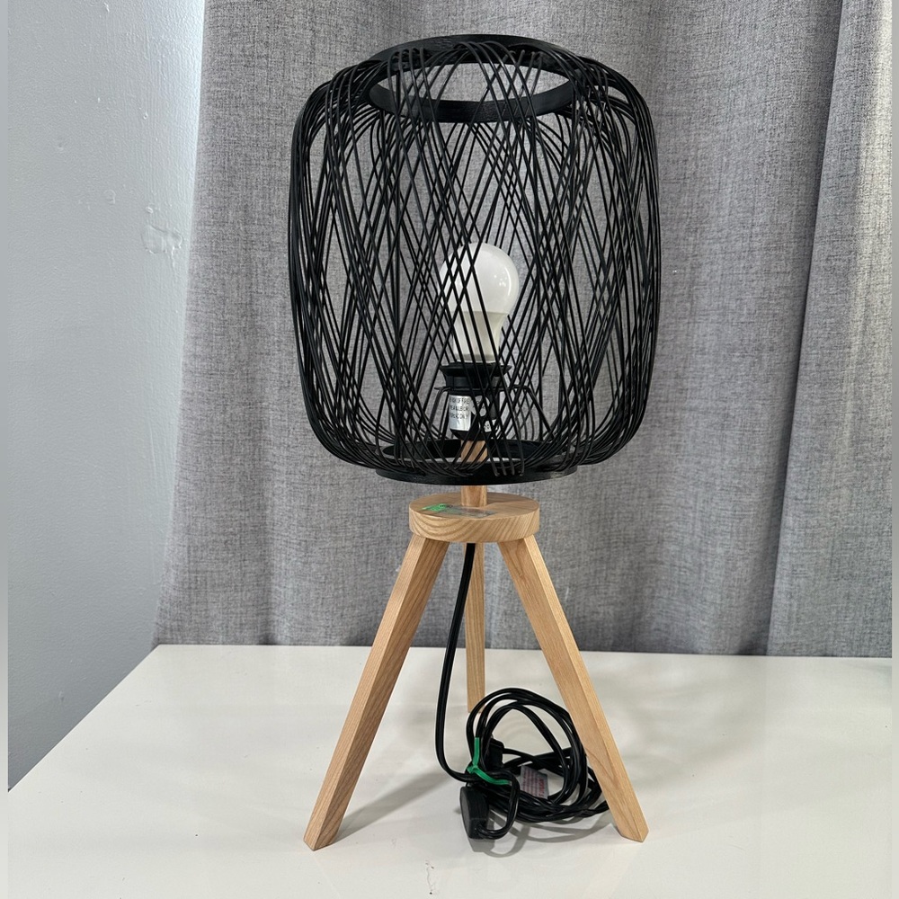 Caged table lamp with a black finish and wood tripod base.